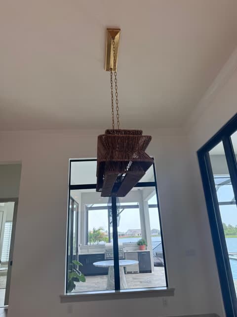 Candelabro colgante estilo rama dorada en un vestíbulo de dos pisos con ventanales altos