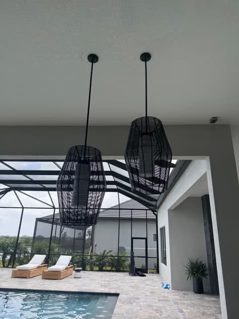 Luces colgantes negras instaladas sobre una terraza de piscina en construcción