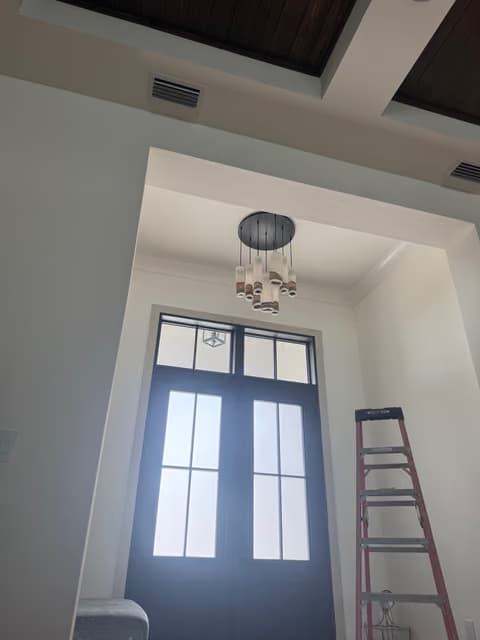 Entrada principal con puertas dobles de vidrio altas y una nueva lámpara colgante
