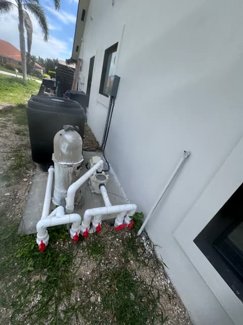 Sistema ablandador de agua y filtración con tubería de PVC blanca montada en una pared exterior