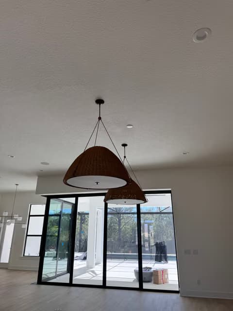 Lámpara colgante de madera instalada en una habitación luminosa con ventanas de marco negro