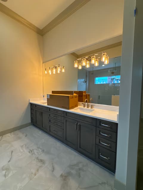 Doble tocador de baño con nueva iluminación colgante y gabinetes oscuros
