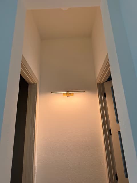 Pasillo con una nueva lámpara colgante y un aplique de pared instalados