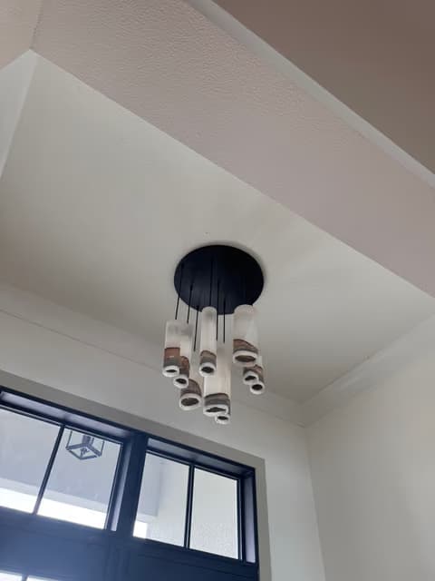 Candelabro redondo instalado cerca de una ventana de marco negro bajo un techo alto