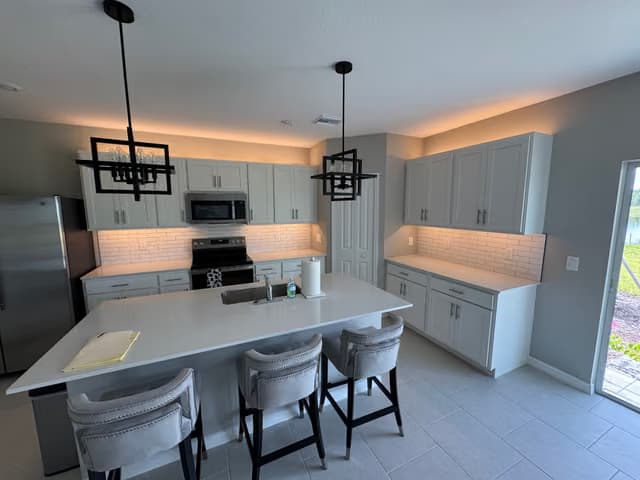 Isla de cocina con nueva iluminación colgante y asientos de barra