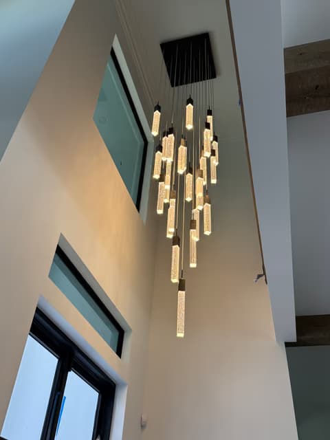 Candelabro lineal moderno con pendientes de varilla de vidrio instalado cerca de una ventana