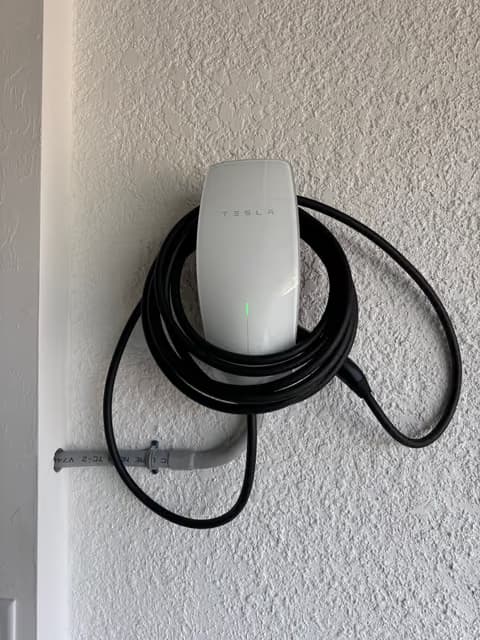 Cargador de pared Tesla para vehículo eléctrico instalado con el cable enrollado ordenadamente