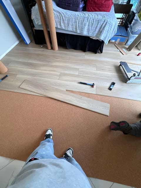 Trabajador arrodillado instalando una tabla de piso de madera