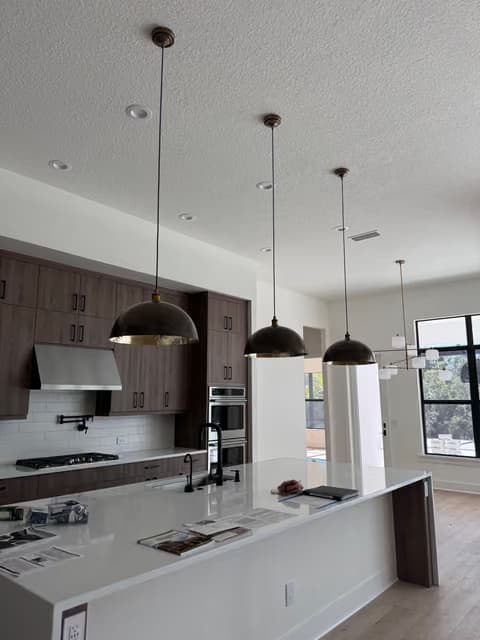 Isla de cocina con iluminación colgante y gabinetes oscuros
