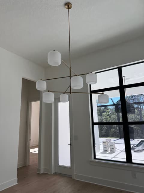 Candelabro de área de comedor con pendientes tipo globo de vidrio cerca de ventanales altos