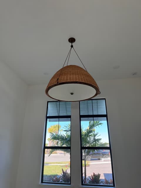 Lámpara colgante tejida instalada en un vestíbulo alto con ventanas