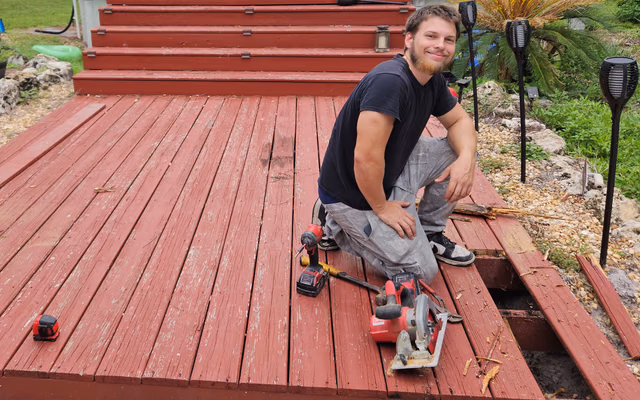 Cullen, KirchCo owner, kneeling on a Southwest Florida deck repair with tools laid out beside him